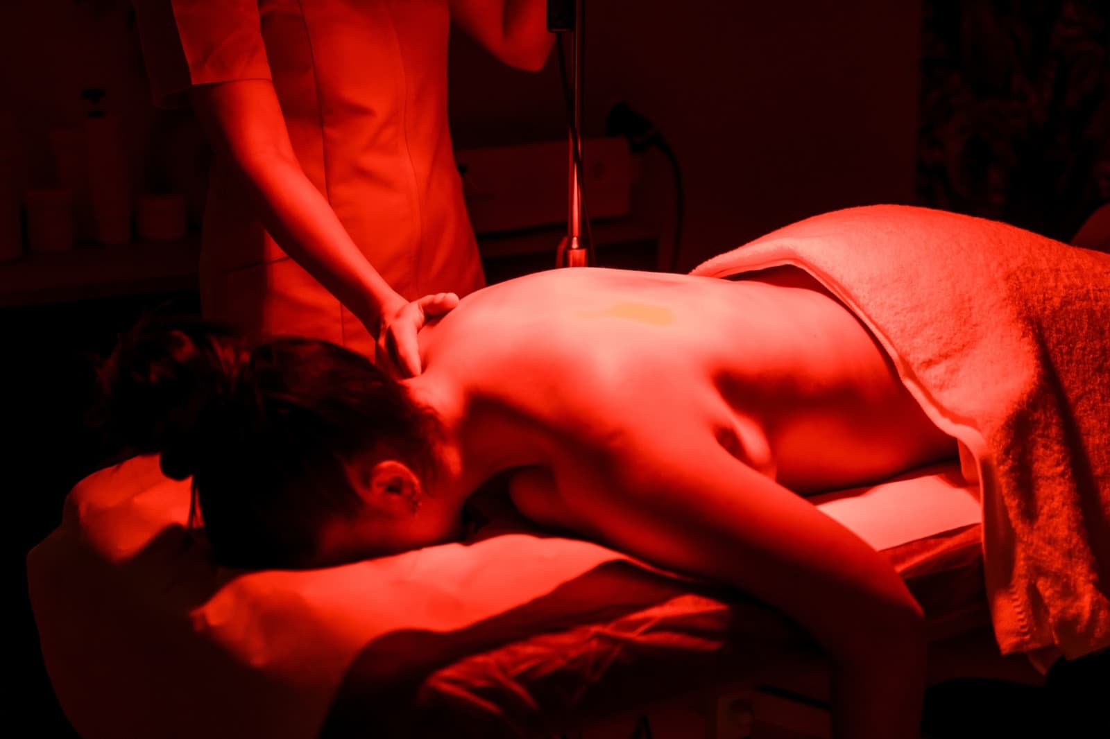 Relaxed member receiving a red light therapy modality in the Addison wellness suite
